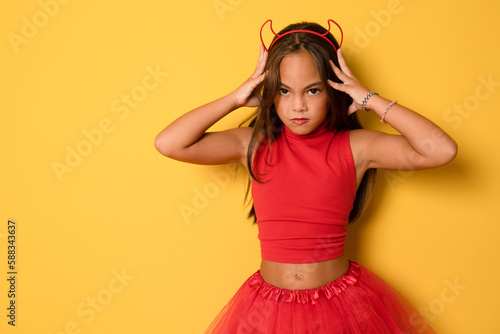 Closeup photo of funny little lady with long hair and headband playing helloween party satan devil character wear read costume isolated yellow color background
