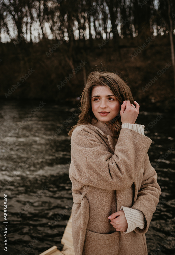 Elegant brunette woman with long wavy hair wearing grey wool coat, holding white handbag and walking at city street on autumn day. Elegant brunette woman with long wavy hair wearing grey wool coat, holding white handbag and walking at city street on autumn day.