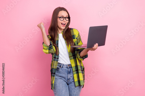 Photo of excited funny girl use netbook raise fist accomplishment isolated on pink color background