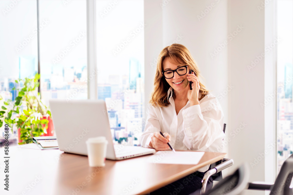Attractive businesswoman wearing white shirt and using mobile phone and computer for work Attractive businesswoman wearing white shirt and using mobile phone and computer for work
