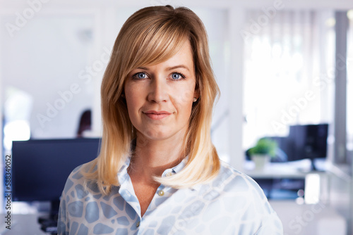 Close-up of a mid aged and blond haired business woman standing at the office