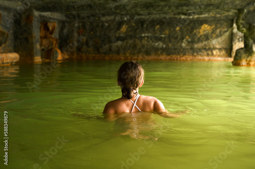 Girl kid child bathe swim in outdoor cave, dirty hot springs. Thermal water bath pool. Healthy natural clay. Yellow green mud. Spa wellness procedures, relax. Family winter vacation in mountain hotel
