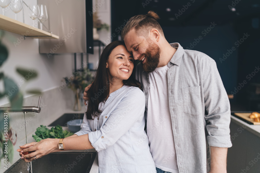 Delighted couple showing tender feelings in kitchen Delighted couple showing tender feelings in kitchen