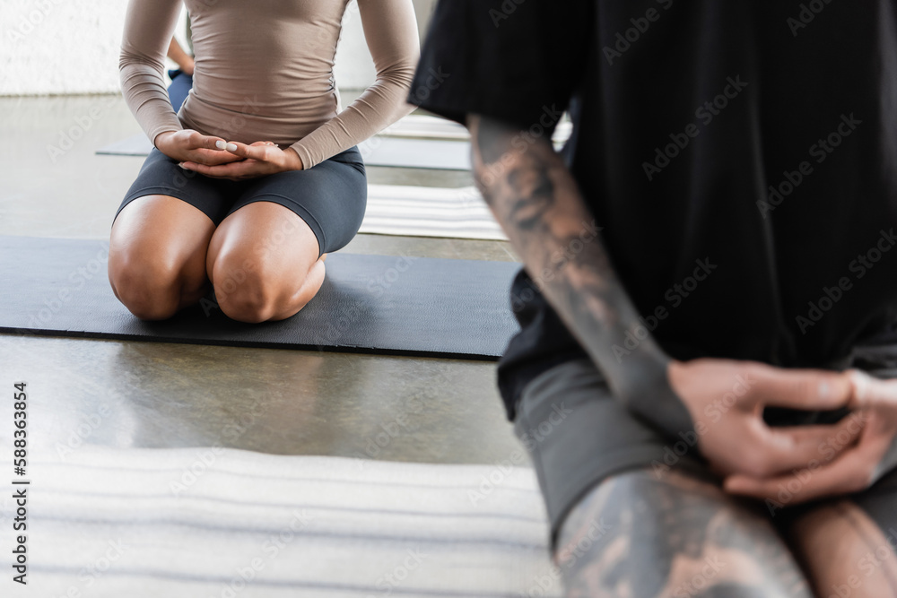 Fototapeta premium Cropped view of african american woman meditating in Thunderbolt pose on yoga mat in studio.
