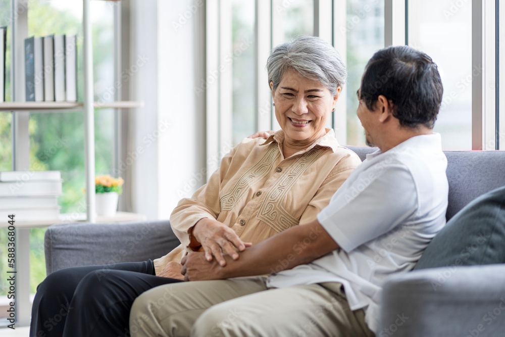 Asian couple, elderly man and woman sitting on the sofa having fun chatting together at home. Concept: health insurance, life insurance, retirement happiness. Asian couple, elderly man and woman sitting on the sofa having fun chatting together at home. Concept: health insurance, life insurance, retirement happiness.
