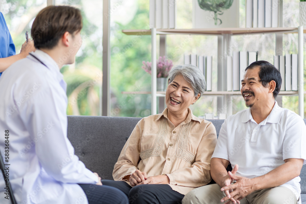 Asian couple Elderly men and women sit on sofas having fun and having fun talking with doctors who come to check their health at home. Asian couple Elderly men and women sit on sofas having fun and having fun talking with doctors who come to check their health at home.