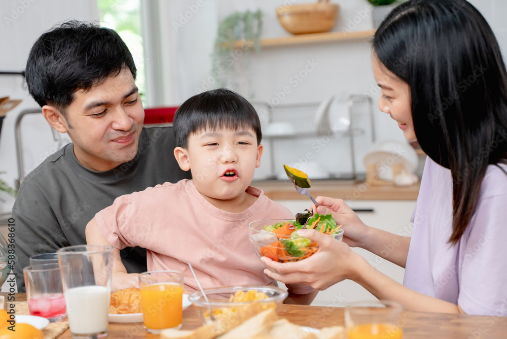 happy family together. Asian parent eating breakfast with little son in the kitchen.