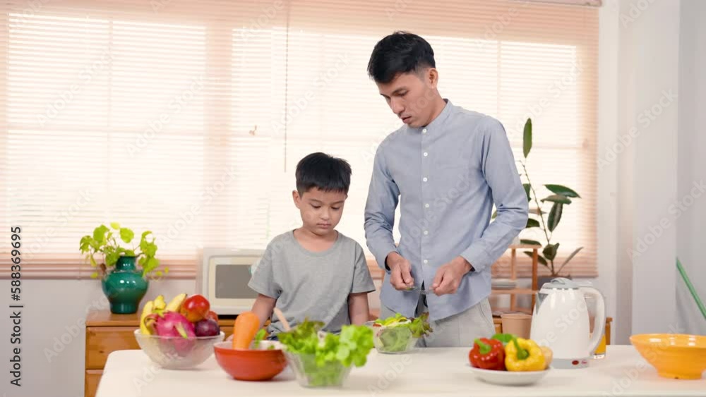 4K, Asian handsome dad teaching son cook help make this vegetable salad for mom, Let mom taste and eat salad in her spare time, It is family activity on weekends, both enjoyed cooking. 4K, Asian handsome dad teaching son cook help make this vegetable salad for mom, Let mom taste and eat salad in her spare time, It is family activity on weekends, both enjoyed cooking.