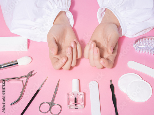 Fotografia Nail salon close up of female well-groomed hands and freshly-manicured fingernails with pink background