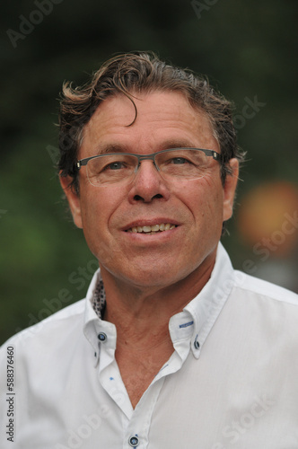 Outdoor portrait of 60 year old man wearing white shirt and eyeglasses