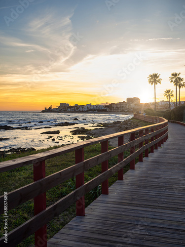 Beach of coastal Benalmadena town. View from a footbridge at sunset. Malaga, Andalusia, Spain photo