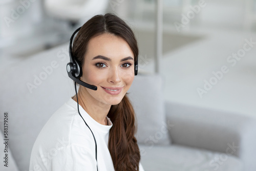 Smiling woman with headset and laptop looking at the camera. Remote work as a mobile operator, support service.