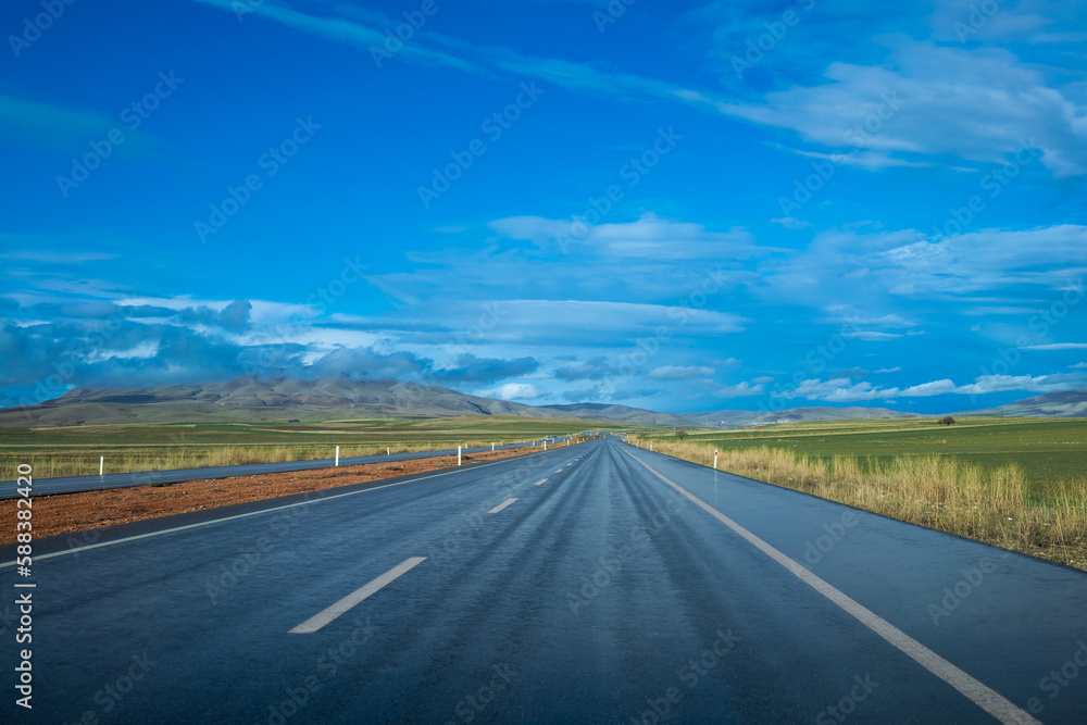 rain-soaked highway and blue sky with clouds