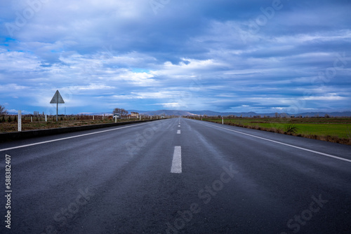 rain-soaked highway and blue sky with clouds