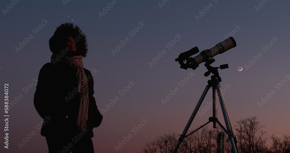 Woman astronomer looking at the starry skies and crescent Moon with a telescope.