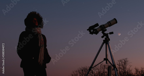 Woman astronomer looking at the starry skies and crescent Moon with a telescope.