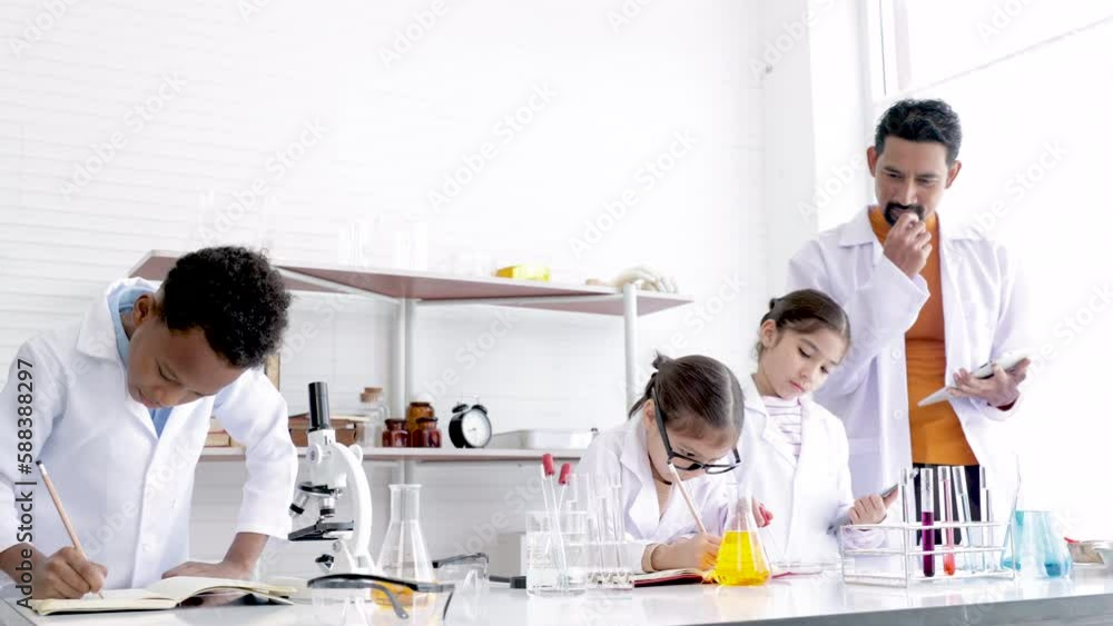 Primary school kid education in science laboratory classroom concept, students in gown uniform research or report experiments in Chemistry lab, children having fun with scientific equipment Primary school kid education in science laboratory classroom concept, students in gown uniform research or report experiments in Chemistry lab, children having fun with scientific equipment