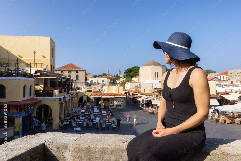 Fototapeta premium Woman Tourist Traveler at Ruines in the historic Old Town of Rhodes, Greece. Sunny Morning.