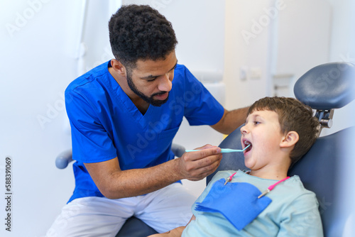 Liitle boy sitting on a dentists chair during dentist examination.