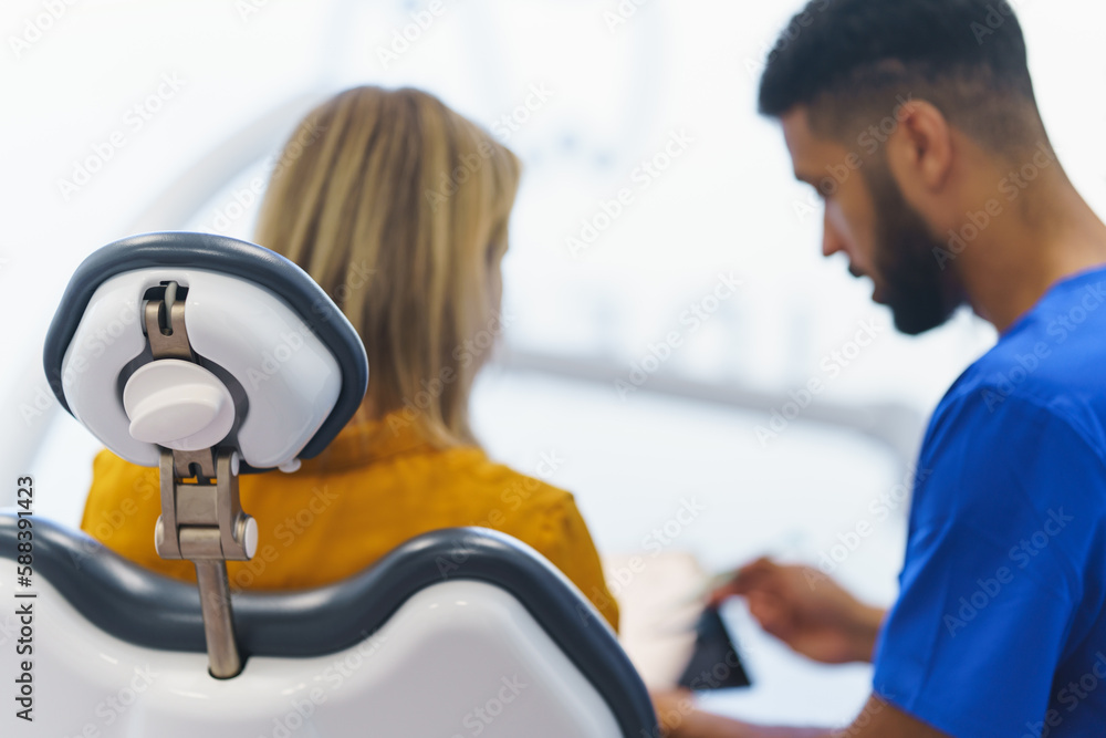 Obraz premium Rear view of multiracial dentist and patient sitting in a dentists chair.