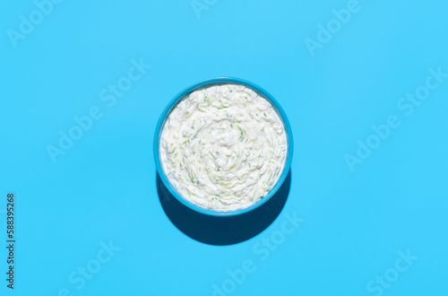 Foto Tzatziki sauce bowl top view on a blue background