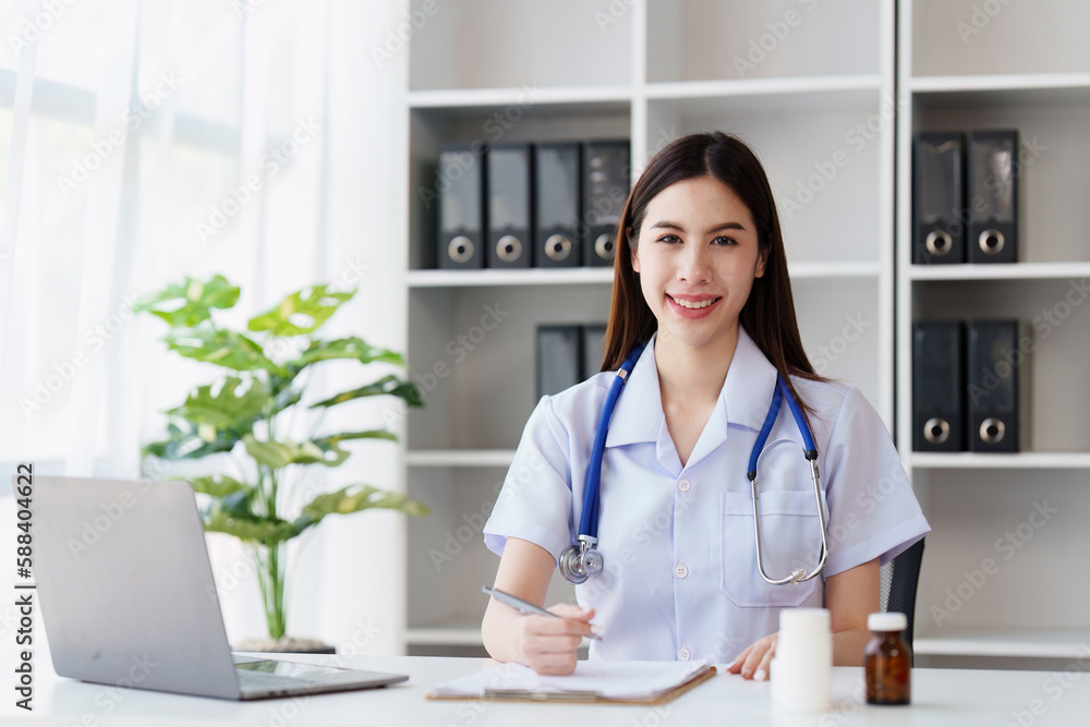 Smiling Happy and Beautiful Doctor working on laptop at clinic, health care, medical, healthy concept Smiling Happy and Beautiful Doctor working on laptop at clinic, health care, medical, healthy concept