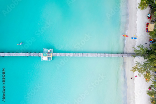Tourist canoeing by wooden pier in turquoise sea and the beach on summer at tropical island