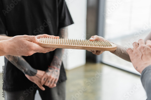 Cropped view of coach giving sadhu board to man in yoga class.