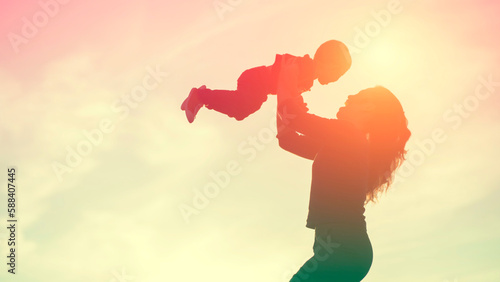 Mother encouraged her son outdoors at sunset, silhouette concept