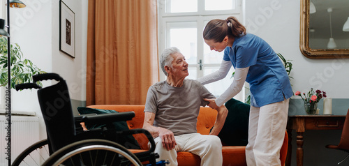 Tableau sur toile Young nurse helping senior man to stand up.