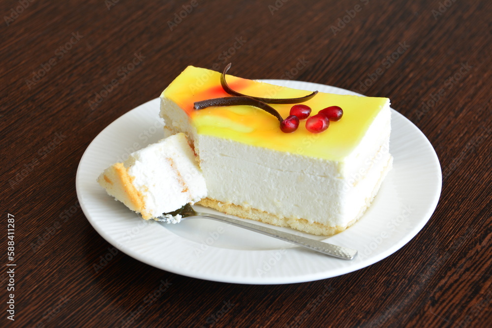 A piece of lemon cheesecake with a spoon on white saucer, close-up A piece of lemon cheesecake with a spoon on white saucer, close-up