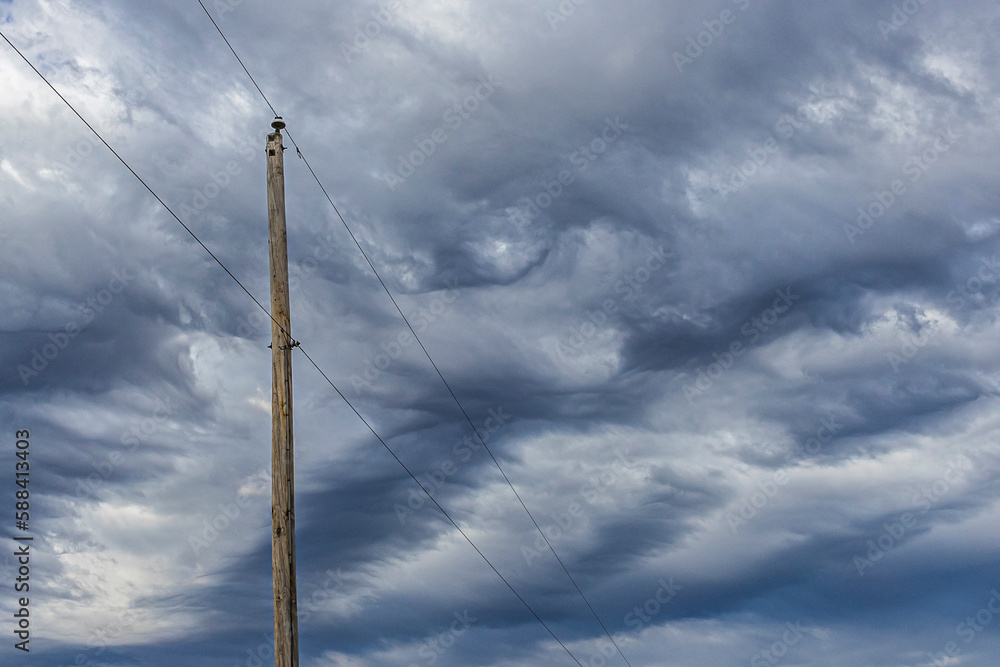 An electric pole and wires with dark storm clouds. An electric pole and wires with dark storm clouds.