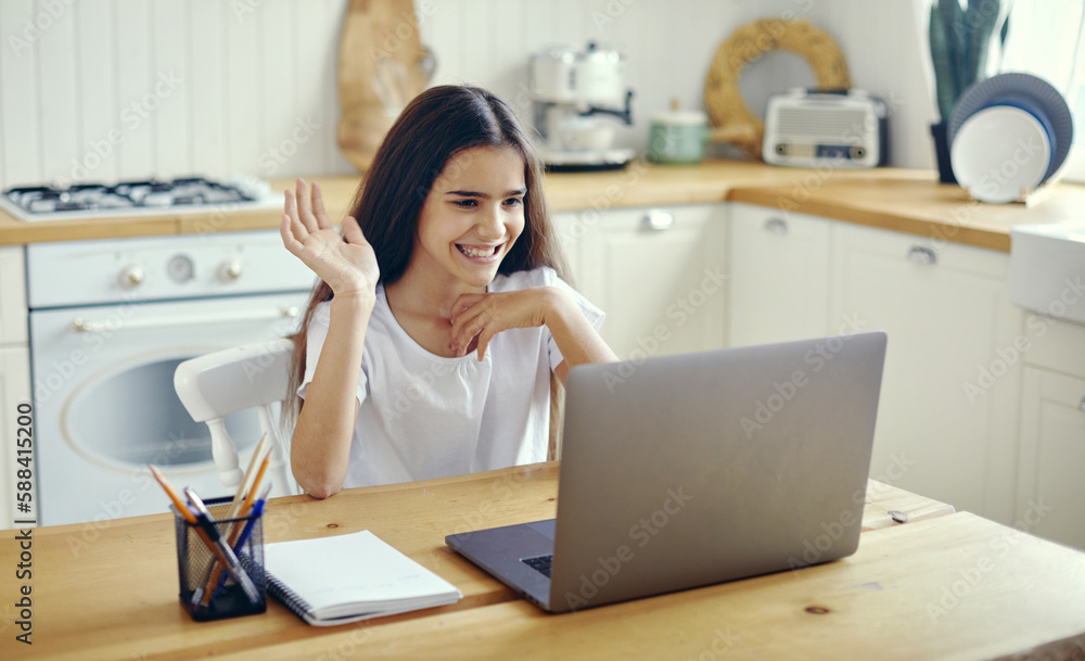 Pretty pre-teen girl using laptop greeting online tutor Pretty pre-teen girl using laptop greeting online tutor