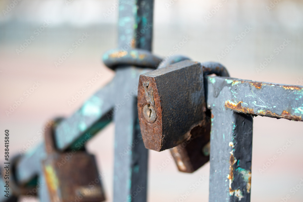 Old rusty padlock hanging on a mesh fence Old rusty padlock hanging on a mesh fence