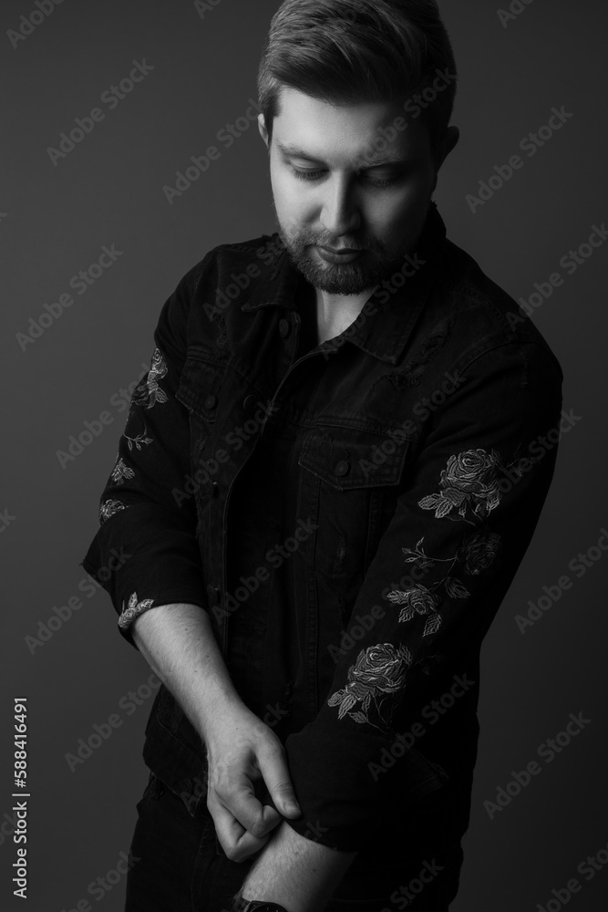 Black and white studio portrait of a handsome male model wearing a black jacket with embroider roses on it. He is caucasian with light hair and he is in his 20s.
Black and white studio portrait of a handsome male model wearing a black jacket with embroider roses on it. He is caucasian with light hair and he is in his 20s.