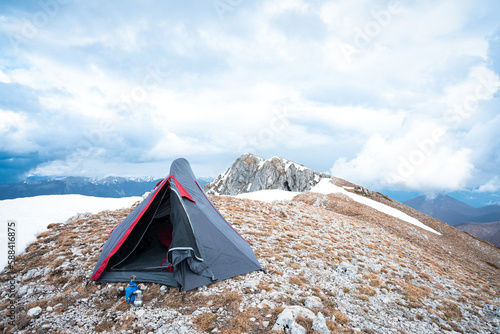 (Selective focus) Stunning view of a camping tent placed on the top of Monte Pratillo with snowcapped mountains in the distance, Prato di Campoli, Veroli, Frosinone, Italy.