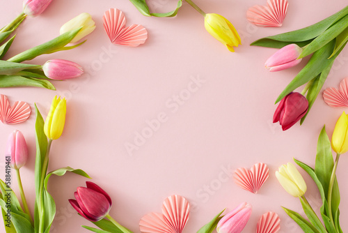Women's Day concept. Flat lay composition made of pink origami paper hearts colorful tulips flowers on pastel pink background with empty space in the middle © Goncharuk film