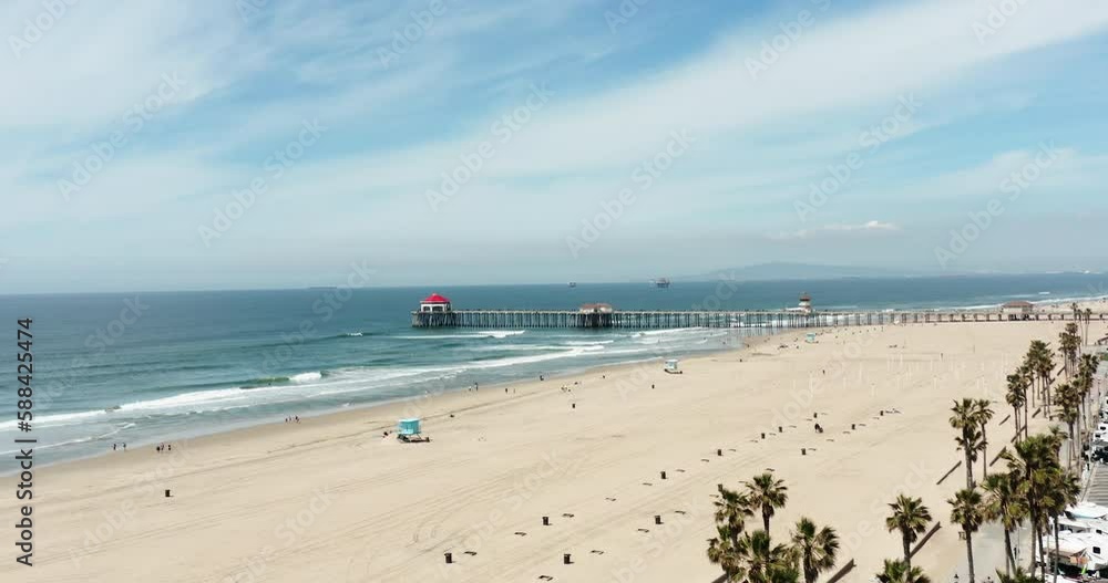 Shooting from below of Huntington Beach Pier with people and shopping areas. Aerial flyover and surveying of the pier and people on the Southern California coast, revealing a view of the Pacific Ocean Shooting from below of Huntington Beach Pier with people and shopping areas. Aerial flyover and surveying of the pier and people on the Southern California coast, revealing a view of the Pacific Ocean