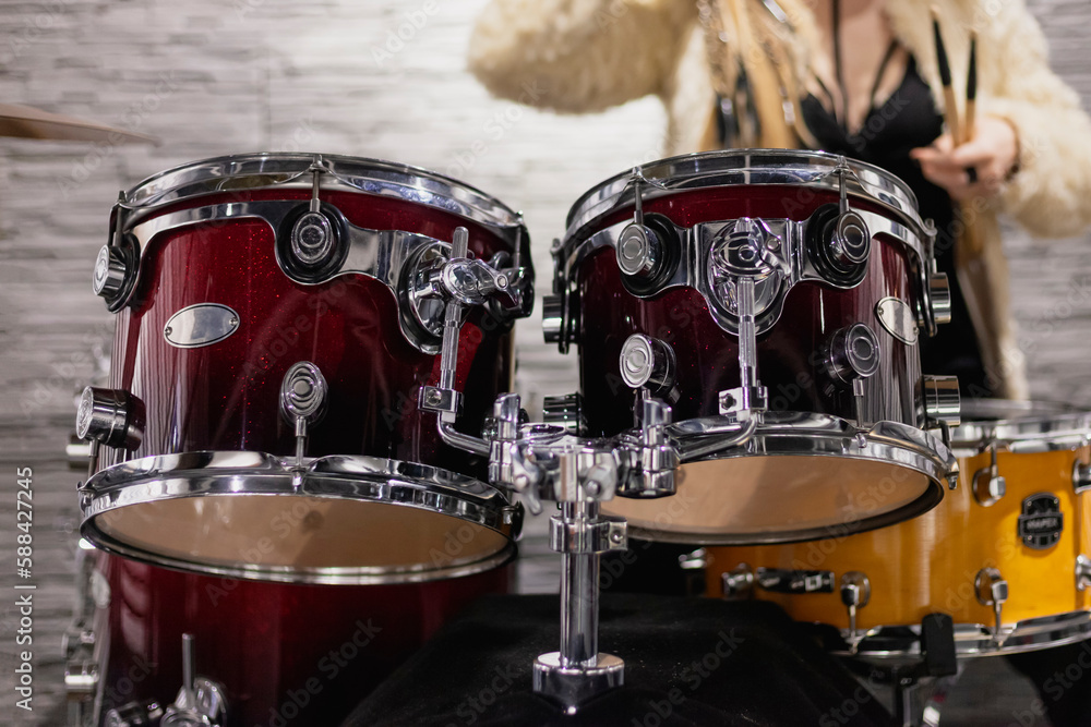 Close-up of a drums, young blonde girl behind it.