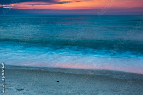 the light of the setting sun is reflected in the gray of the sea