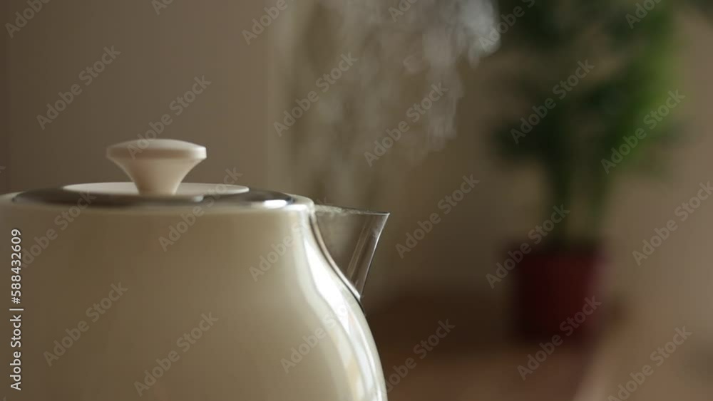 Close up of boiling water and steam comes out of white modern electric