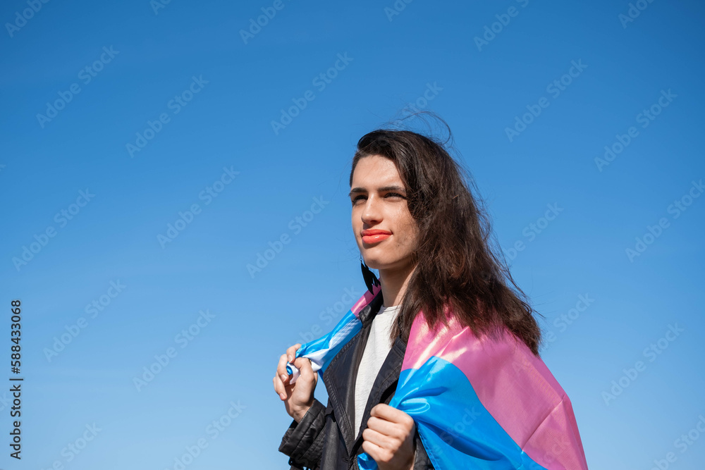 Transgender woman draped with the trans flag outdoors. LGTBIQ+ activism Transgender woman draped with the trans flag outdoors. LGTBIQ+ activism