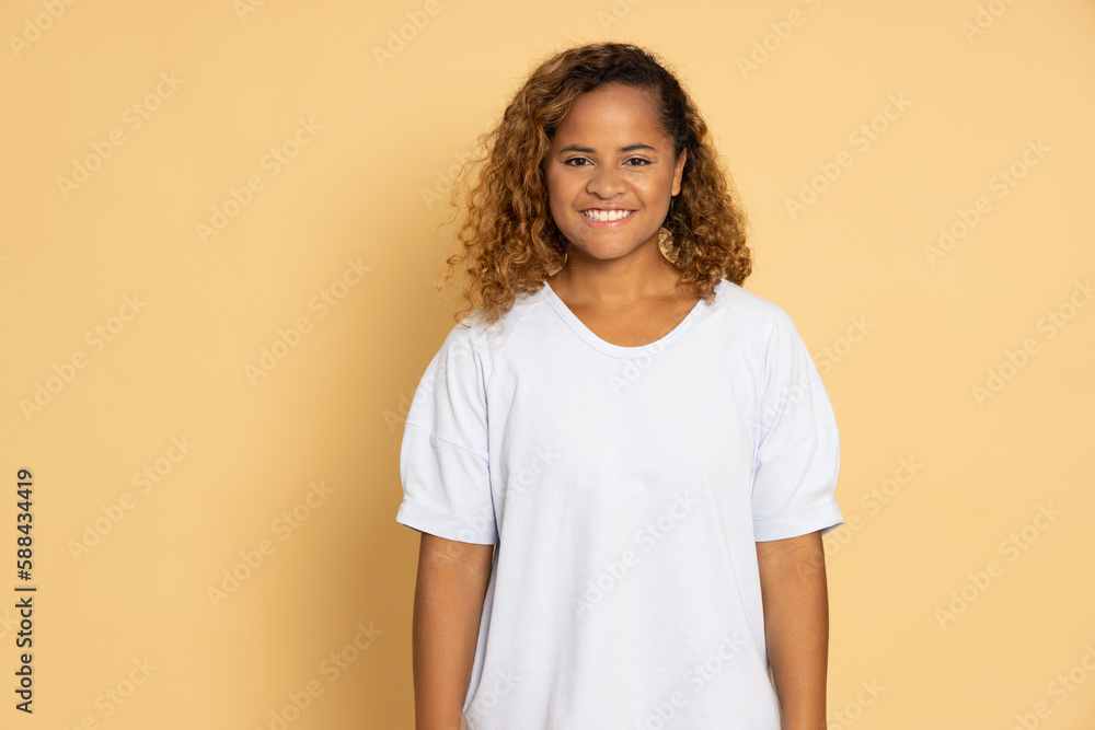Portrait of happy african american woman smiling and looking at camera isolated over light brown studio background Portrait of happy african american woman smiling and looking at camera isolated over light brown studio background