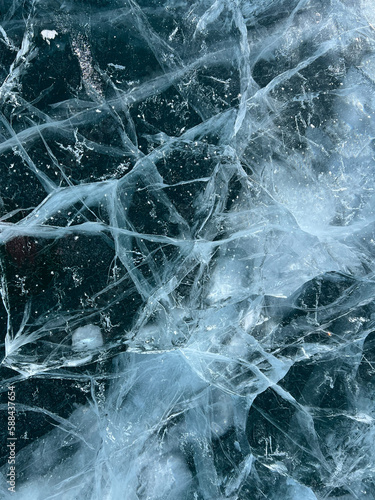 The natural texture of winter ice with white bubbles and cracks on a frozen lake. Abstract background of ice and cracks on the surface of frozen Lake Baikal