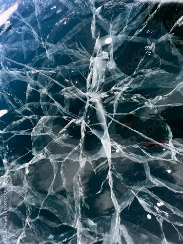 The natural texture of winter ice with white bubbles and cracks on a frozen lake. Abstract background of ice and cracks on the surface of frozen Lake Baikal