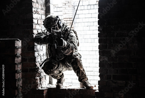 Black and white image of rappeller - police officer or soldier in tactical gear descending from a height to attack and fight. Tactical rappelling, anti-terror or counter terrorism operation in ruined photo
