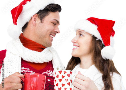 Happy couple with santa hats holding mug