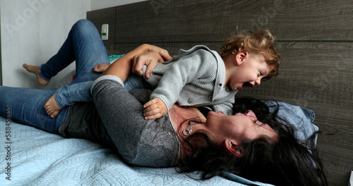 Baby and mother having fun together rolling on bed