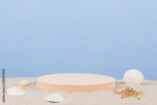 Empty round beige platform podium with sea shells and starfish on white beach sand over blue background. Minimal creative composition background for cosmetics or products presentation. Front view