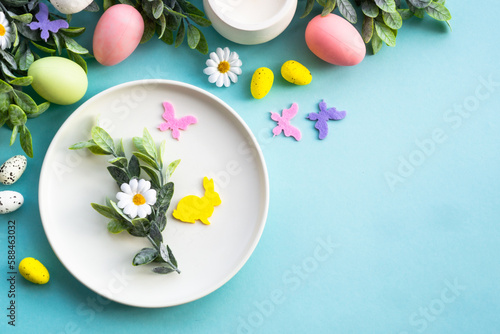 Easter table setting, Easter food background. White plate with eggs, spring flowers, green leaves and butterfly. Flat lay.